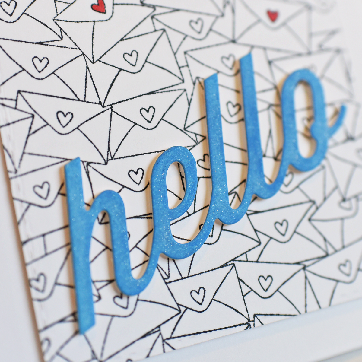 die cut blue cursive hello on a background of multiple small envelopes with hearts