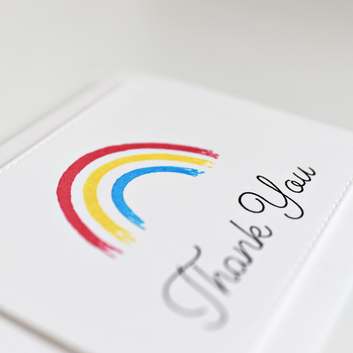 close up of red, yellow, and blue striped rainbow handstamped thank you card